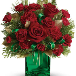 Red roses and carnations in a green glass vase with gold and green ribbon