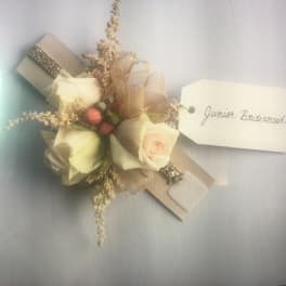 Small corsage with cream roses and a name tag reading Junior Bridesmaid