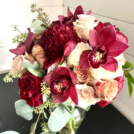 Bouquet of red orchids and pale roses in a glass vase