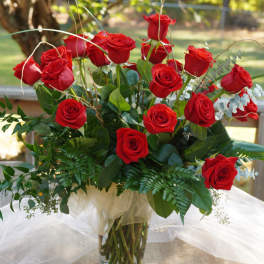 Red roses arranged in a clear glass vase with greenery