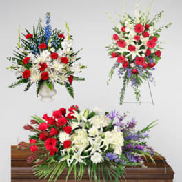Three floral funeral sprays with red, white, and purple flowers around a casket