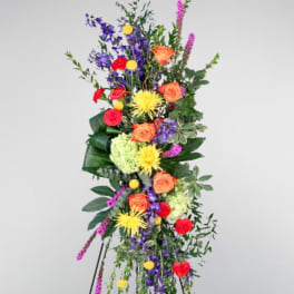 Tall standing floral spray with orange roses, purple blooms, and yellow flowers