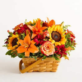 Basket arrangement with sunflowers, orange lilies, and red roses