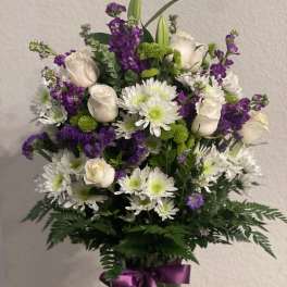Bouquet of white roses, white daisies, and purple flowers in a glass vase