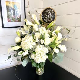 White floral arrangement in a glass vase with a Happy New Year balloon
