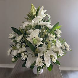 White lilies and daisies arranged in a white vase