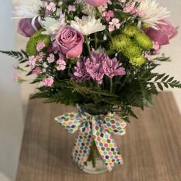 Bouquet of pink roses, white daisies, and green mums in a glass vase