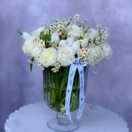 White roses and small daisy flowers arranged in a glass vase