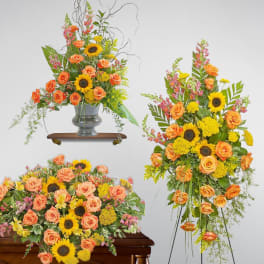 Set of orange rose and yellow sunflower sympathy arrangements with casket spray, easel spray, and urn piece.