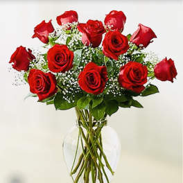 Red roses arranged in a clear glass vase with baby's breath