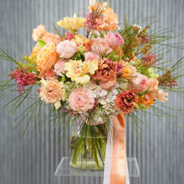Peach and pink bouquet in a glass vase with long ribbon tails