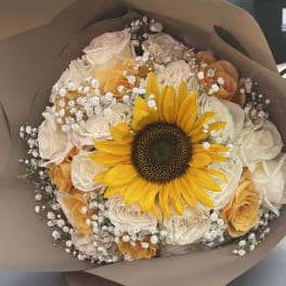 Bouquet of yellow sunflower and pale roses wrapped in brown paper