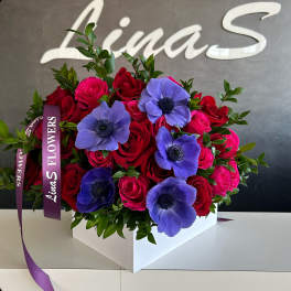 Bouquet of red and pink roses with purple anemones in a white box