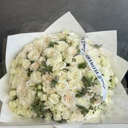 Large bouquet of white roses wrapped in white paper