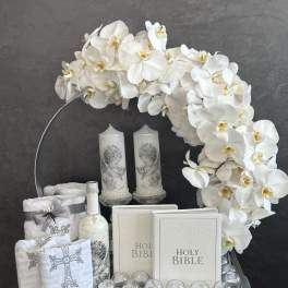 White orchid arrangement with candles, Holy Bibles, and religious keepsakes
