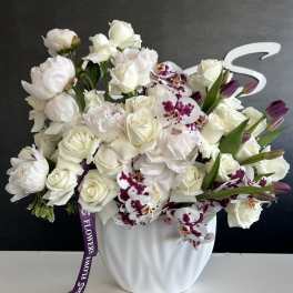 White floral arrangement with roses and orchids in a white vase