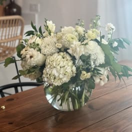 White floral bouquet in a clear glass vase on a wooden table