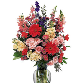Mixed bouquet of red, pink, yellow, and purple flowers in a glass vase