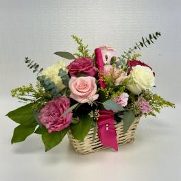 Basket arrangement of pink, red, and white roses with pink carnations and a hot pink ribbon accent