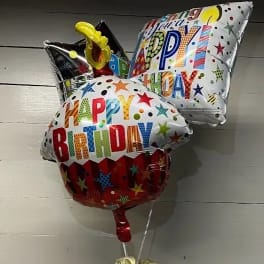 Birthday balloon bouquet in a basket with gift items