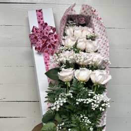 Bouquet of pale pink roses wrapped in heart-patterned paper with a pink bow