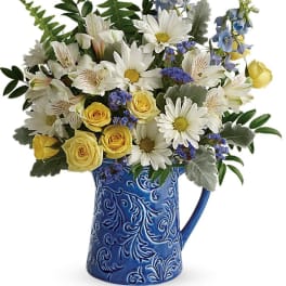 Bouquet of white daisies and yellow roses in a blue ceramic pitcher