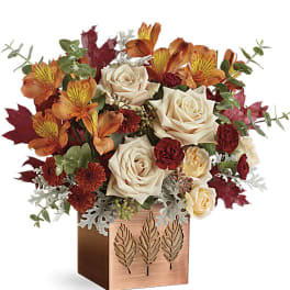 Autumn bouquet of roses and orange flowers in a copper cube vase