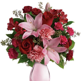 Pink lilies and red roses in a pink glass vase