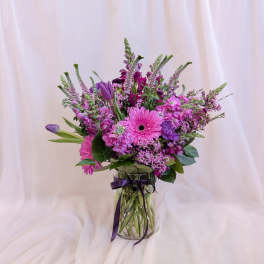 Pink and purple mixed bouquet in a glass vase with a ribbon