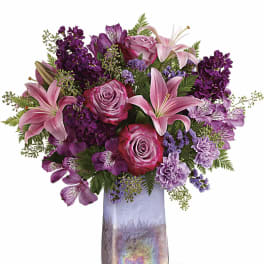 Pink and purple floral arrangement in a tall iridescent vase