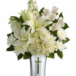 White floral arrangement in a silver vase with a cross