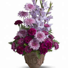 Purple floral arrangement in a decorative urn vase