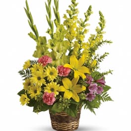 Basket arrangement of yellow and pink flowers with tall green spikes