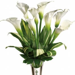 White calla lilies in a silver vase with a cross emblem
