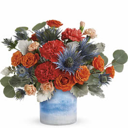 Orange and red flowers arranged in a blue ceramic vase