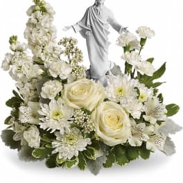 White floral arrangement with a small religious statue in the center