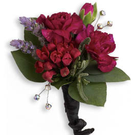 Small magenta boutonniere with green leaves and dangling crystal accents