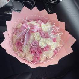 Pink and white rose bouquet wrapped in pink paper with pearl trim