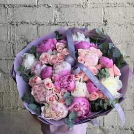 Large round bouquet of pink and white peonies with pale pink roses wrapped in lavender paper and ribbon