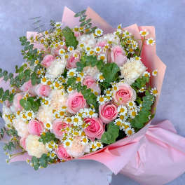 Bouquet of pink roses, white carnations, and daisies wrapped in pink paper