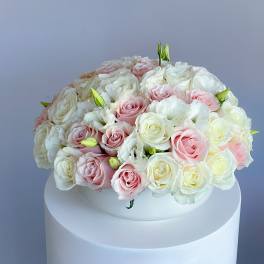 Round bouquet of pink and white roses on a white pedestal