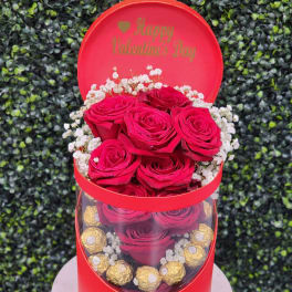 Red roses in a round gift box with chocolates and a Happy Valentine's Day lid