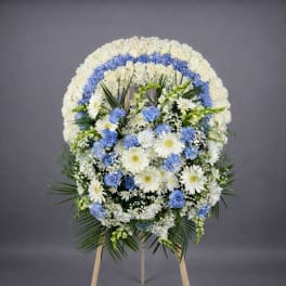 Standing round wreath of white and blue flowers on a wooden easel