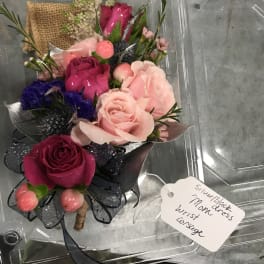 Small bouquet of pink and magenta roses in a clear plastic box