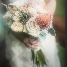 Bridal bouquet of pale roses and a pink dahlia with jeweled butterfly accents