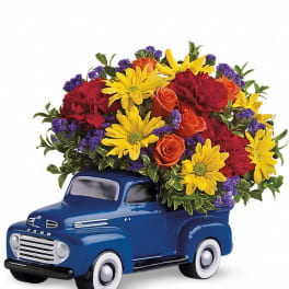 Blue toy truck topped with a colorful flower arrangement