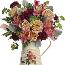 Bouquet of peach roses and pink alstroemeria in a decorative metal pitcher