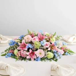 Low pastel floral centerpiece with pink lilies, roses, and blue accents