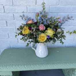 Mixed bouquet in a white pitcher vase with yellow and pink blooms