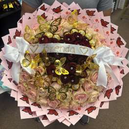 Bouquet of pink and burgundy roses with butterfly decorations and a white ribbon